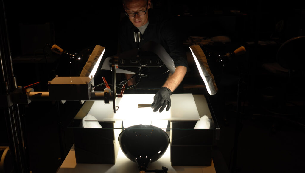 Image displaying a digital imaging specialist taking high-resolution photographs of archival materials.
